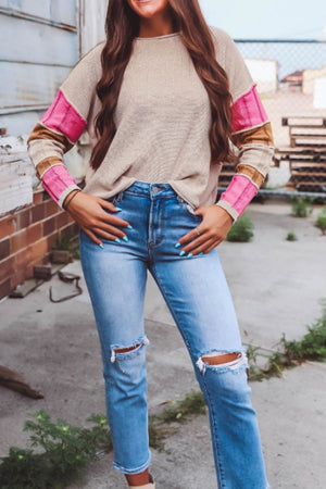 Beige knit sweater with colorblock sleeves in pink and brown, crew neck, long sleeves.