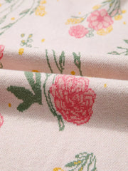 Floral v-neck knit sweater with pink and yellow flowers on a cream background.