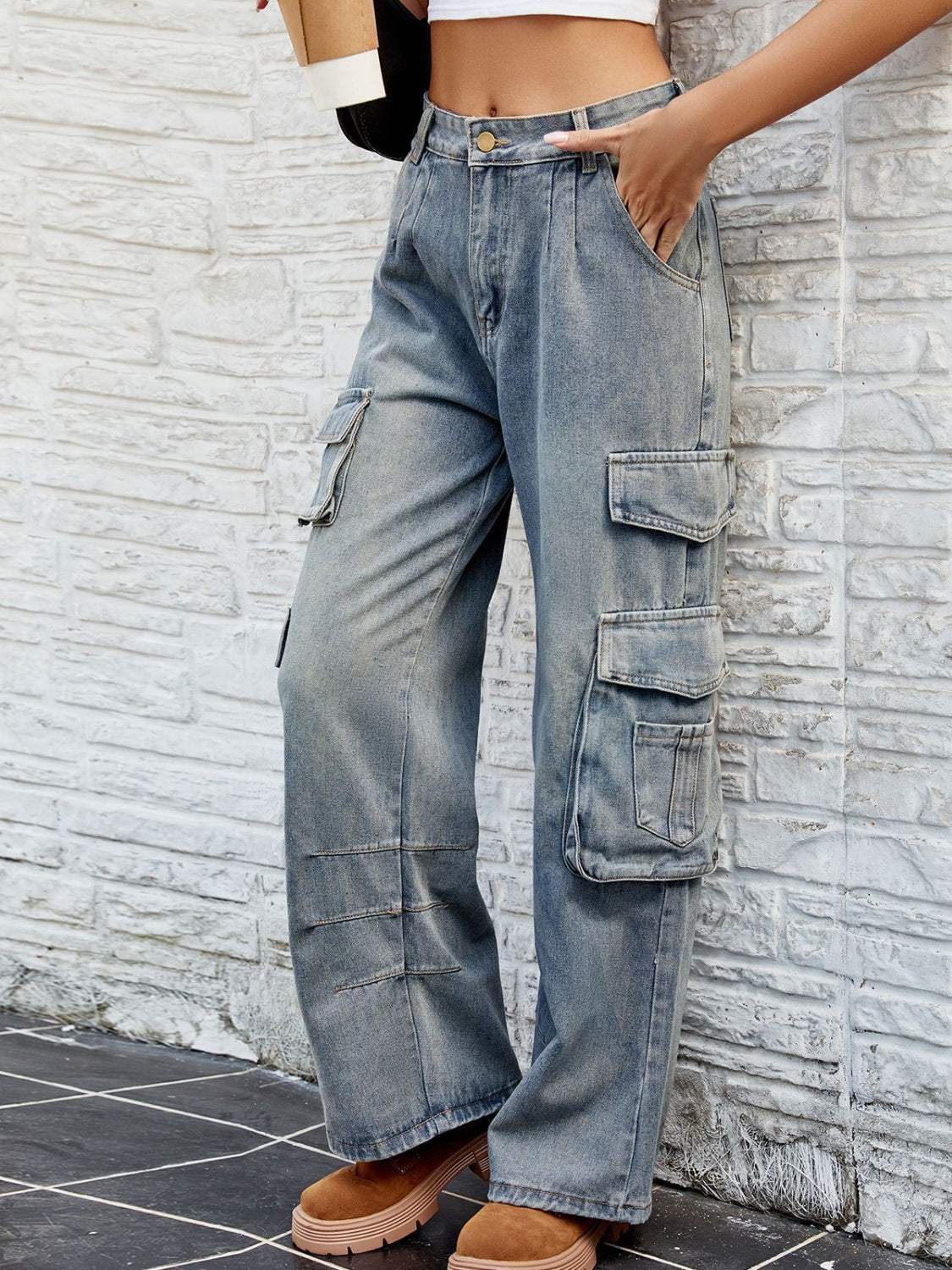 Light wash denim cargo pants with pleated waist and multiple utility pockets.