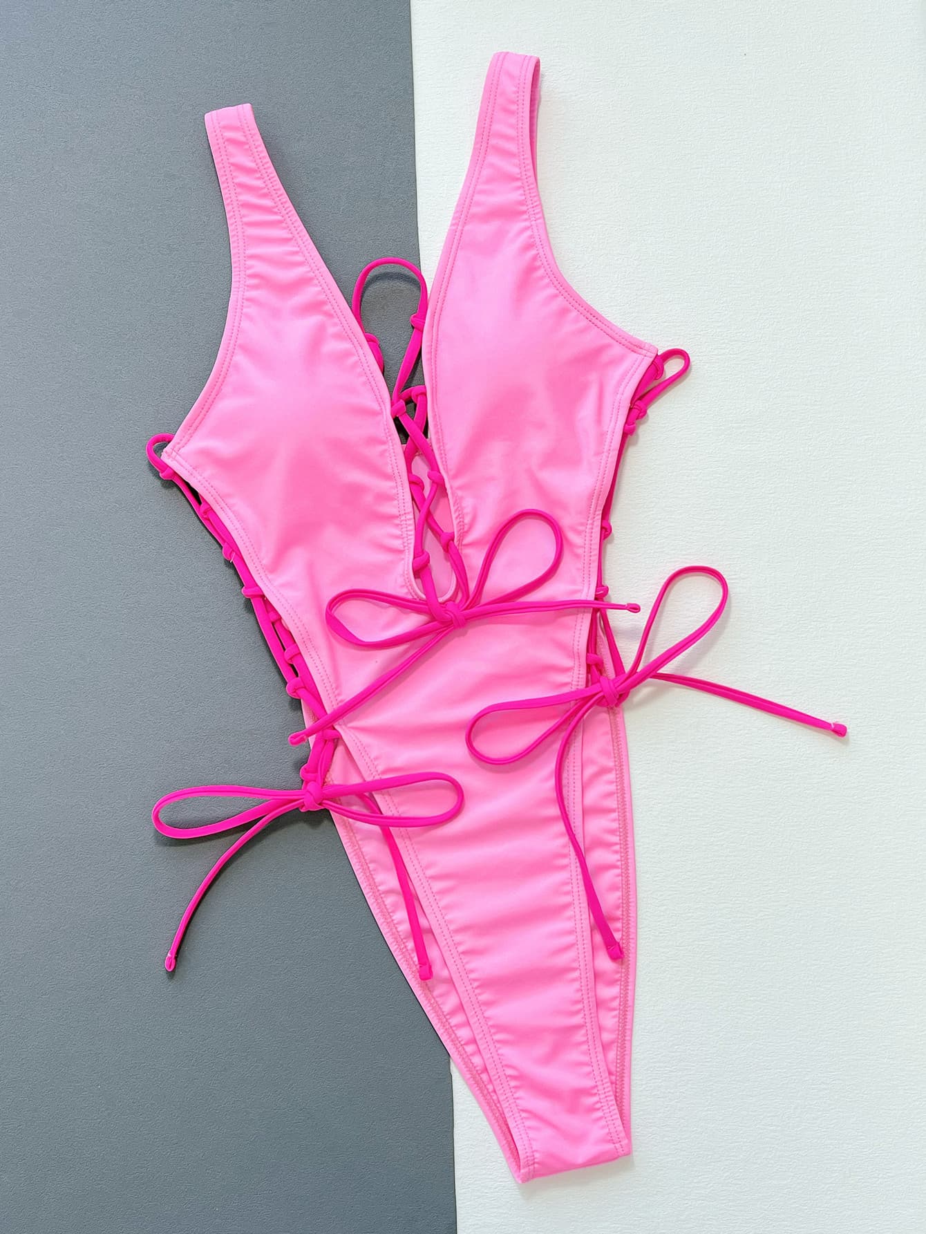 Pink lace-up plunge one-piece swimsuit with adjustable tie sides.