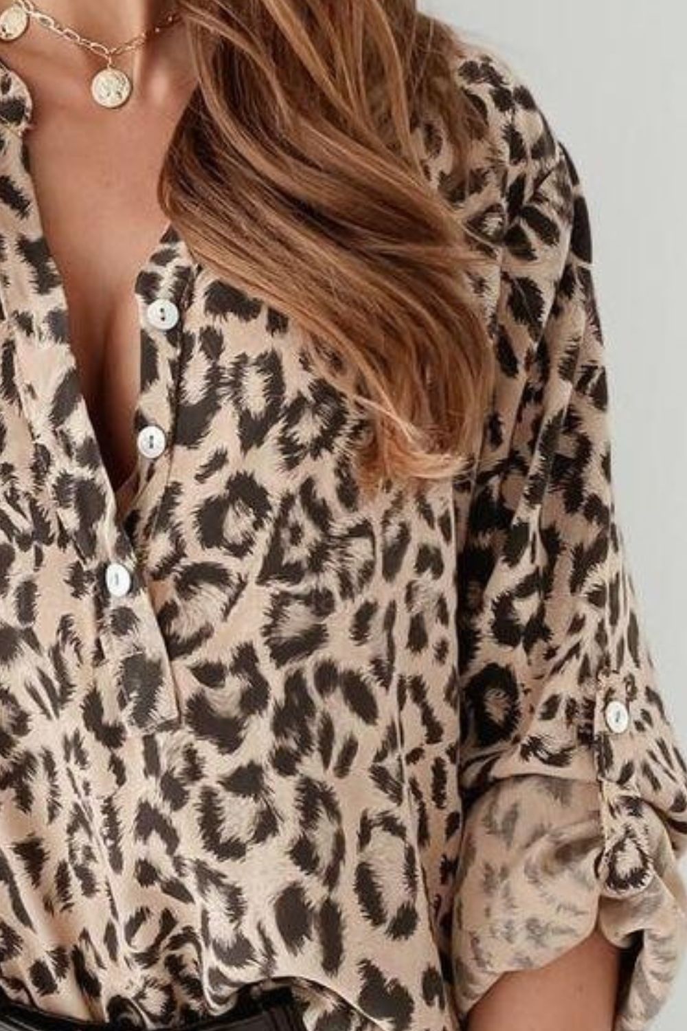 Beige leopard print henley blouse with button front and rolled sleeves.