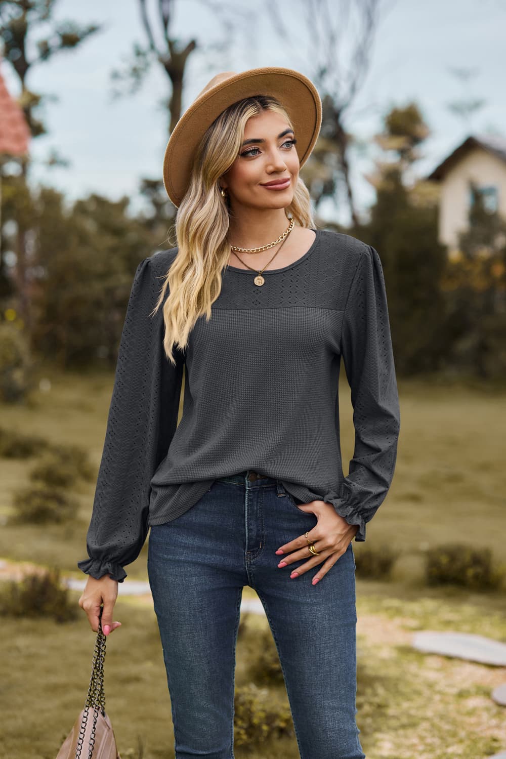 Dark gray waffle knit blouse with perforated detail and ruffled cuffs.