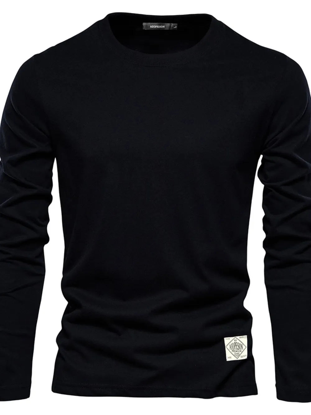 Black crew-neck long-sleeve tee with a textured patch detail on the hem.