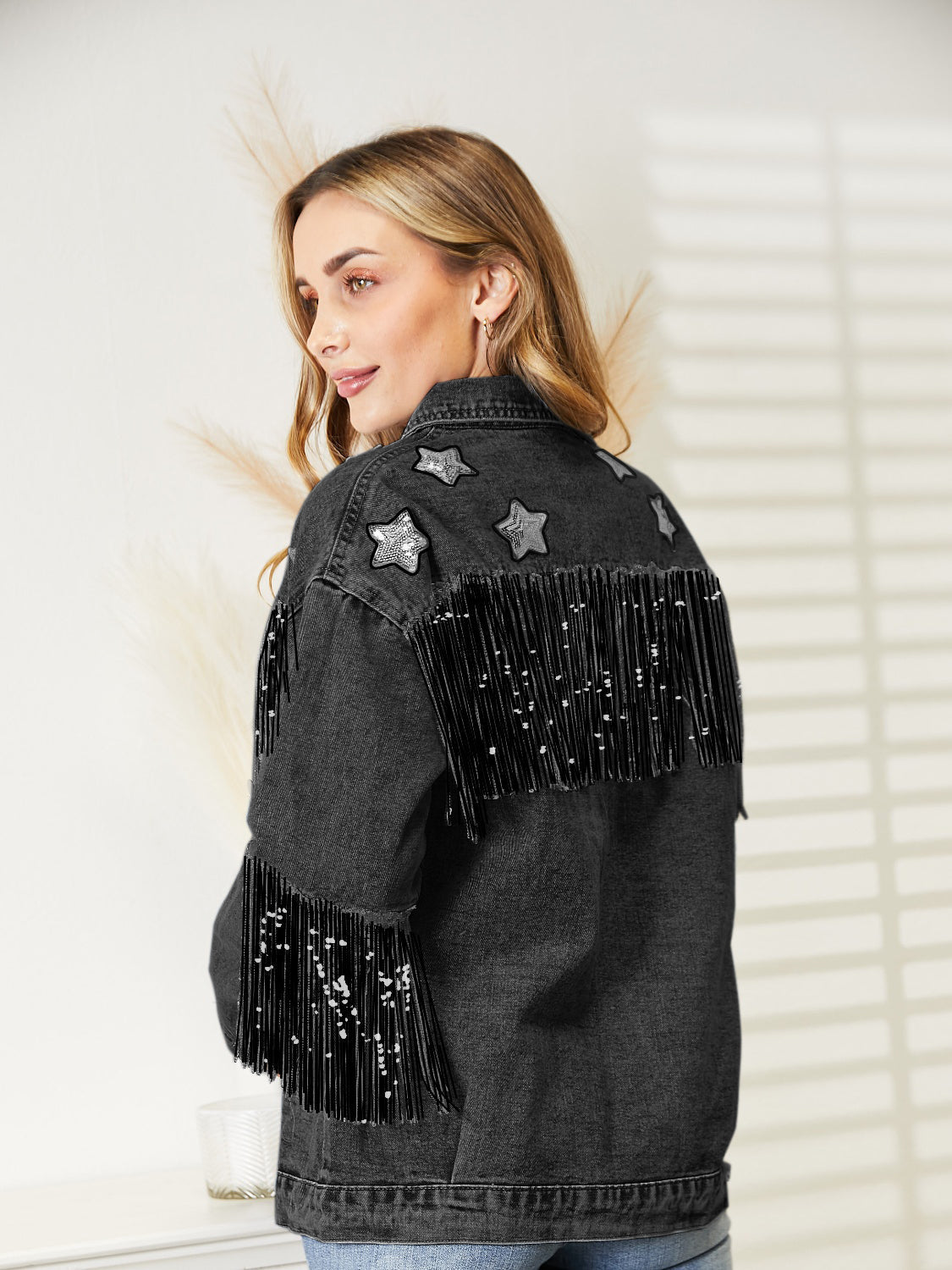 Black denim trucker jacket with star patches and sequin fringe on back and sleeves.