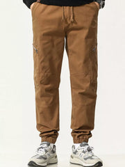 Men's caramel cotton cargo pants with zipper pockets and drawstring waist.