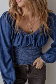 Denim corset blouse with smocked waist and blouson sleeves.