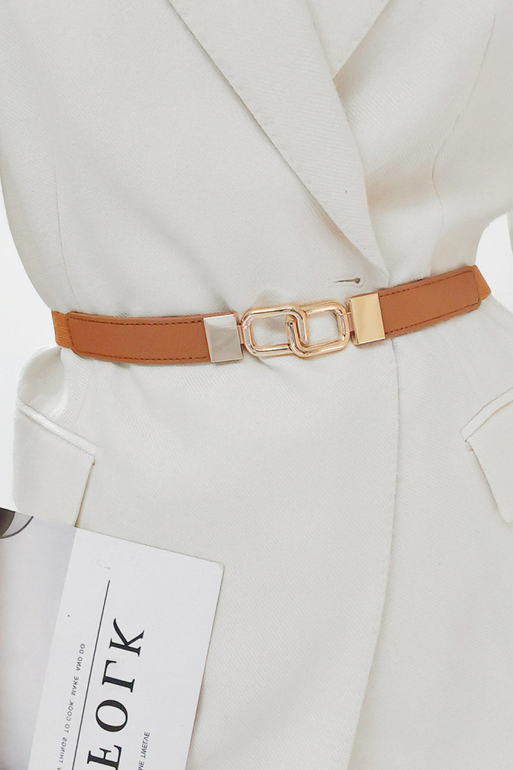 Caramel belt with linked rectangle buckle and gold hardware, worn over a white blazer.