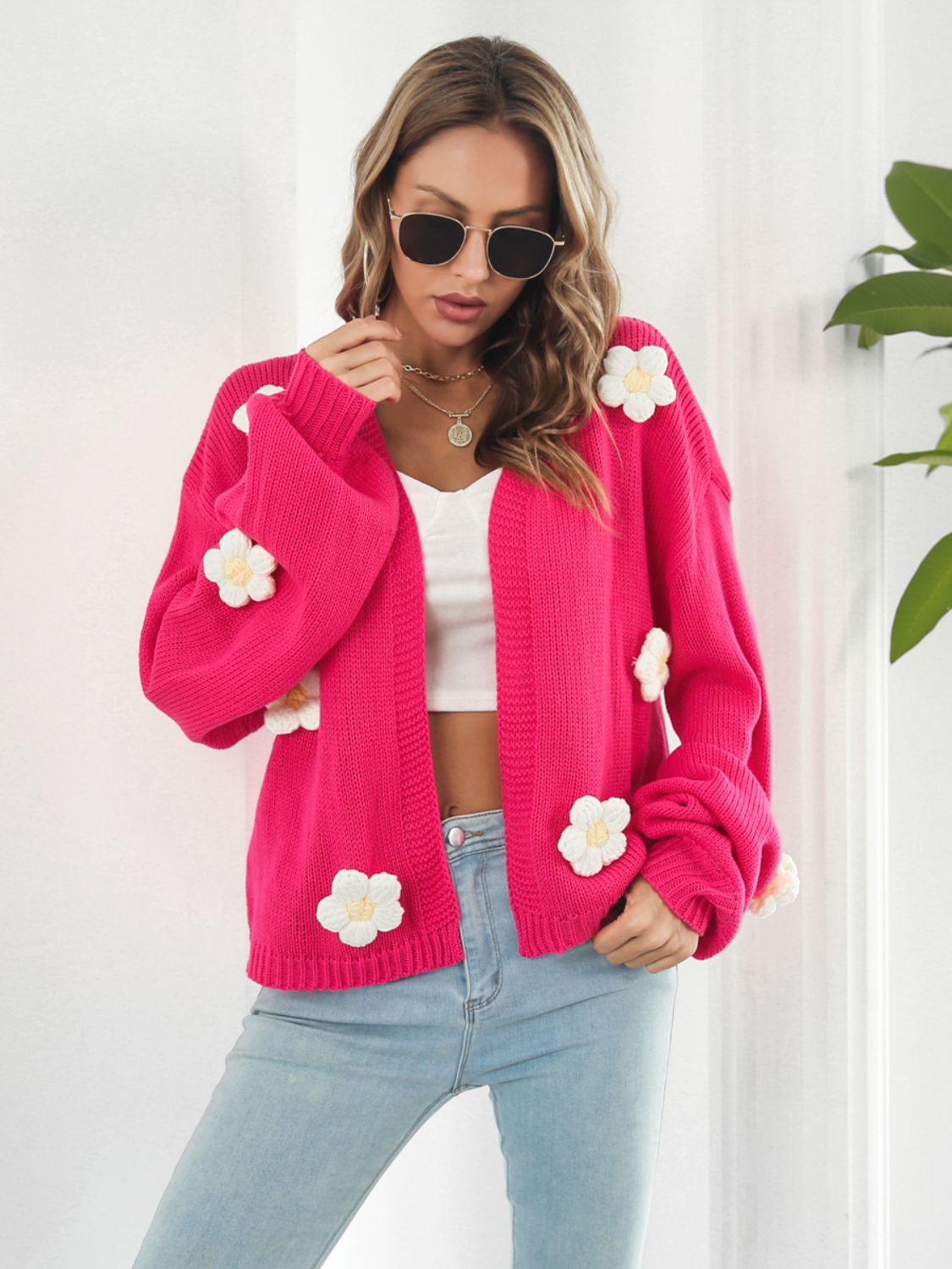 Hot pink knit cardigan with white floral appliqués and balloon sleeves.