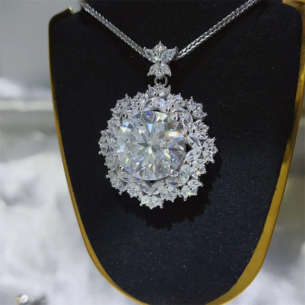 Radiant white cluster pendant necklace with large central stone and floral halo.