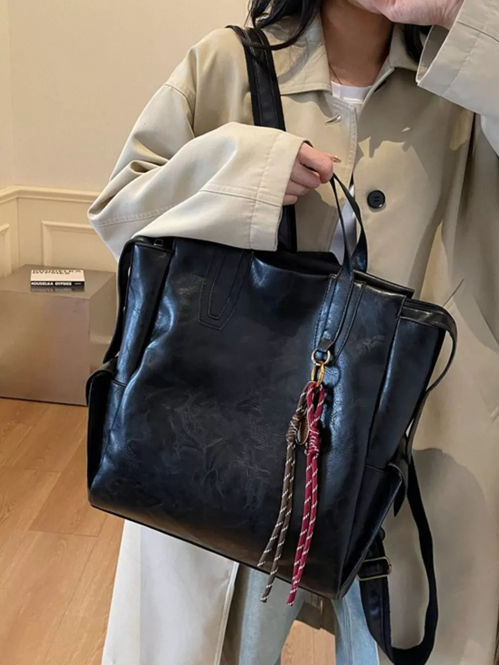 Black leather convertible backpack with tassel detail and side pockets