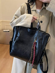 Black leather convertible backpack with tassel detail and side pockets