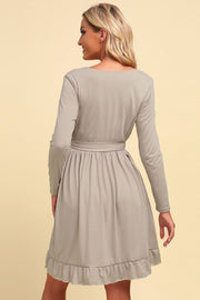Tan wrap dress with long sleeves, belted waist, and ruffled hem detail.