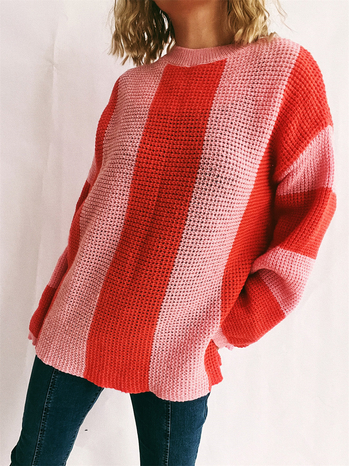 Vertical stripe waffle knit sweater in pink and orange-red with a crew neck.