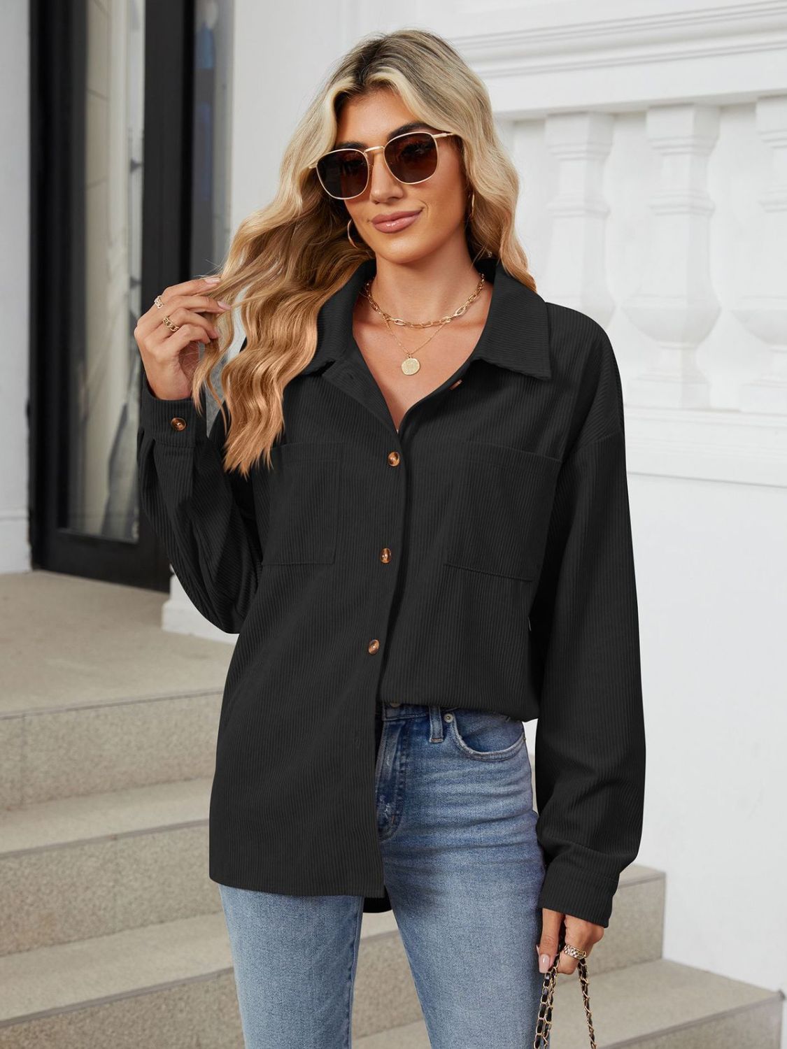 Black corduroy overshirt with button front and chest pockets, styled casually.