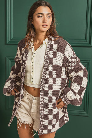 Chic checkered acrylic cardigan with balloon sleeves and open front, styled with a cream top and tan shorts.