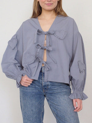 Lavender blouse with heart appliques and tie front, featuring ruffled cuffs and balloon sleeves.