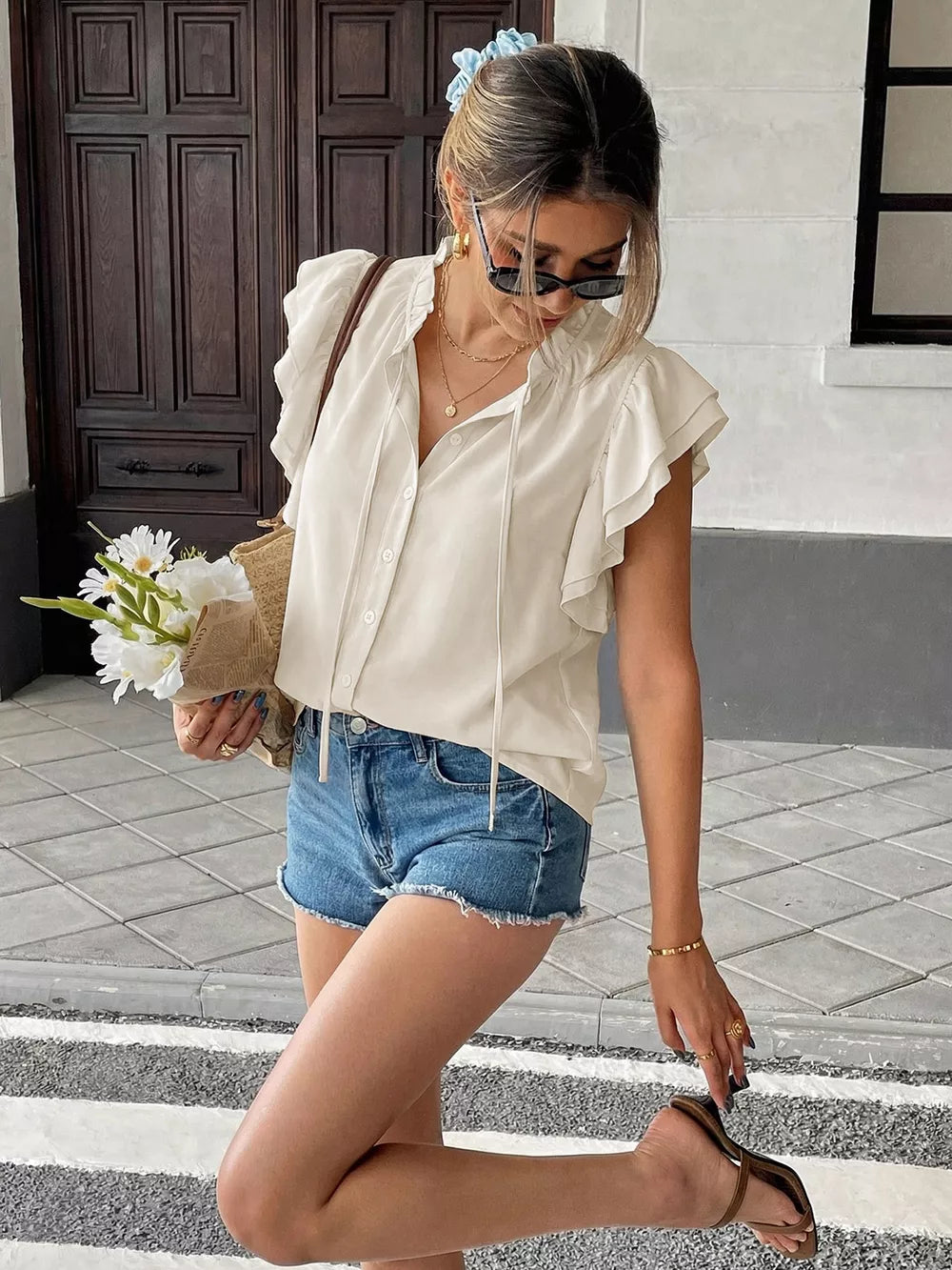 Beige tie-neck maternity overshirt with ruffle sleeves and button-down front.