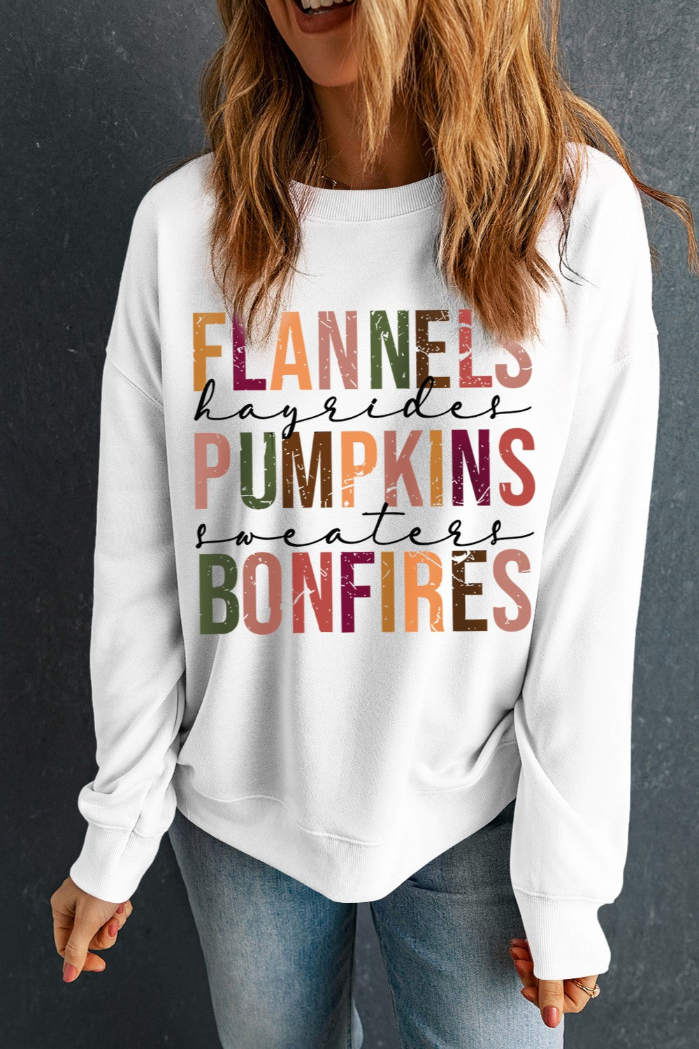 White crewneck sweatshirt with colorful autumn graphic text: Flannels, Hayrides, Pumpkins, Sweaters, Bonfires.