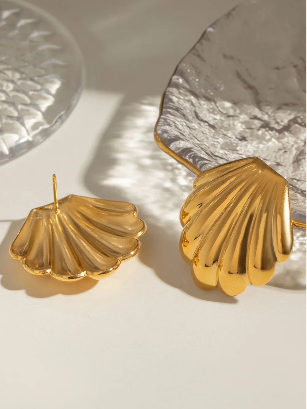 Gold scallop shell stud earrings with textured detail.