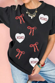 Black cotton t-shirt with sequin heart and bow pattern, short sleeves, crew neck.