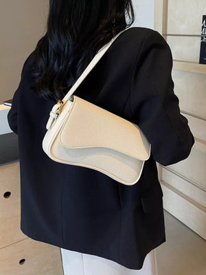 Off-white faux leather crossbody bag with textured finish and gold buckle detail.