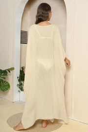 Oversized caftan cover-up in light yellow with wide sleeves and side slits, worn over a bikini.