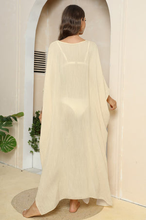 Oversized caftan cover-up in light yellow with wide sleeves and side slits, worn over a bikini.