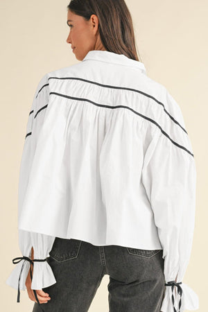 White piped trim blouse with gathered detail and bow tie cuffs.
