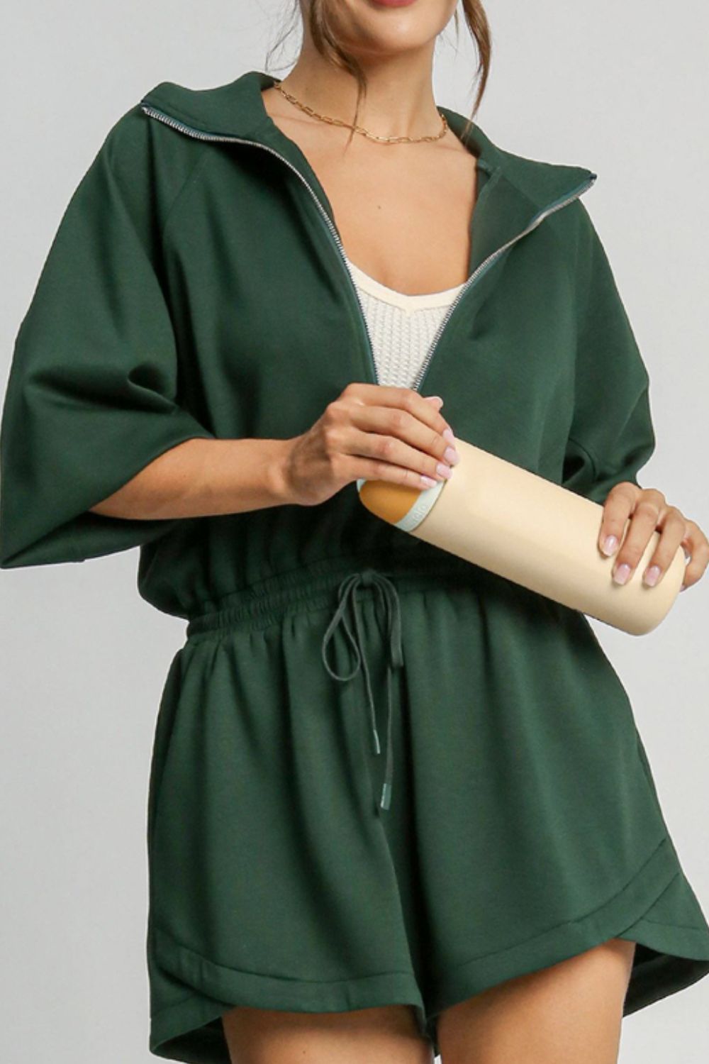 Dark green drawstring waist romper with funnel neck and zip front, short sleeves.