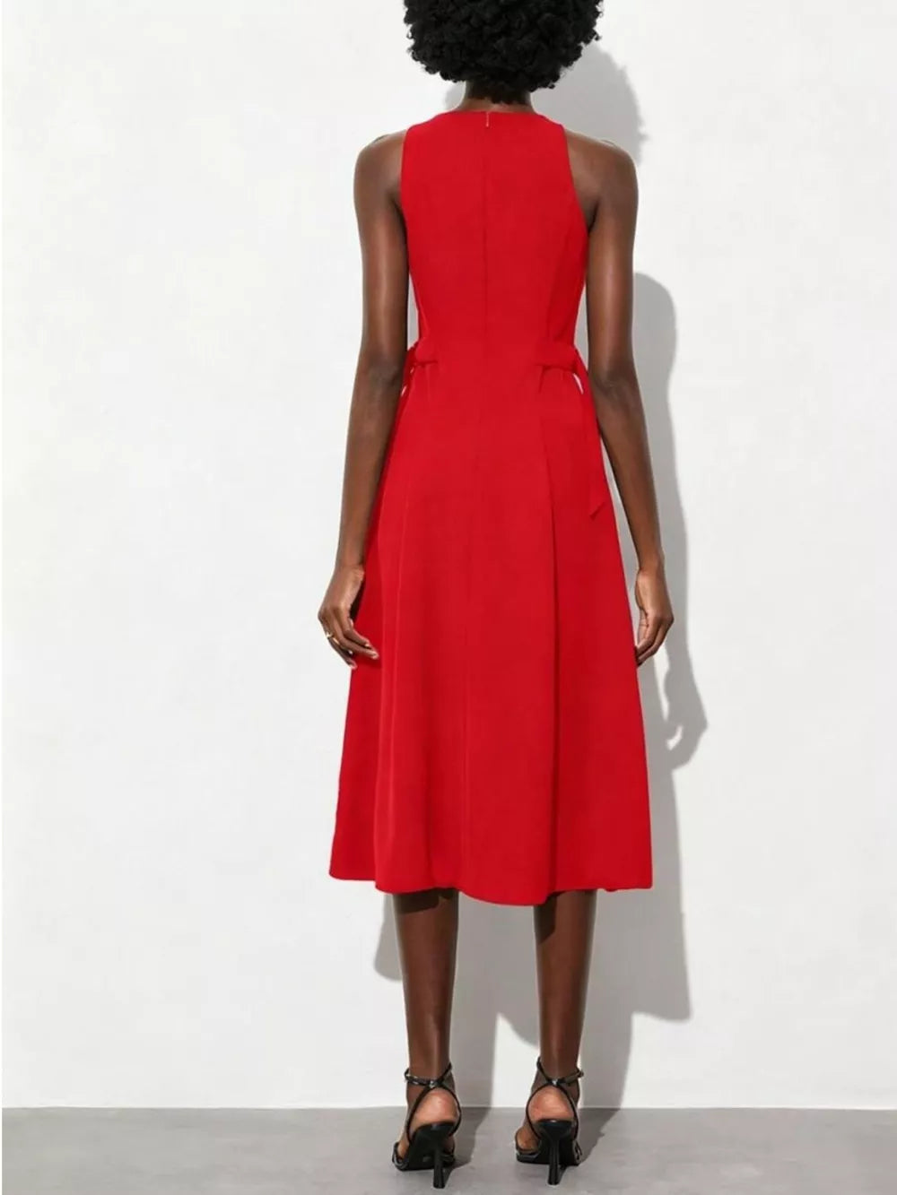 Red A-line midi dress with high neckline, sleeveless, defined waist, and subtle side tie details.