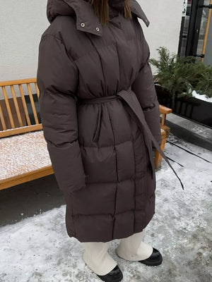 Dark brown padded trench coat with tie belt and hood, quilted puffer jacket style.