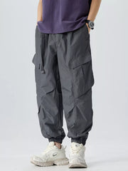 Oversized dark gray cargo pants with adjustable belt and elastic cuffs.