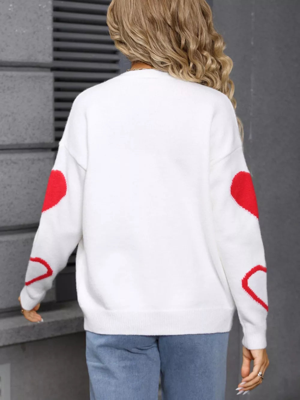 White acrylic knit cardigan with red heart details on sleeves.