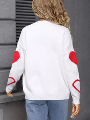 White acrylic knit cardigan with red heart details on sleeves.