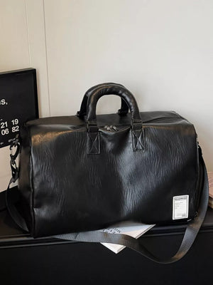 Black pu leather duffel bag with top handles and shoulder strap.