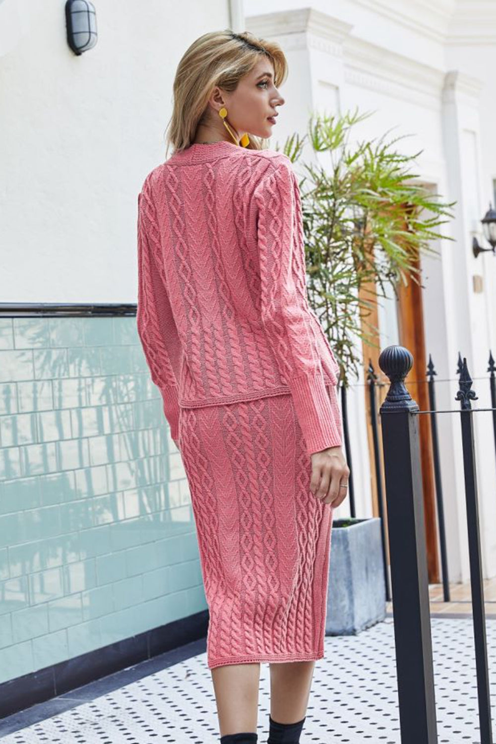 Pink cable knit cardigan and pencil skirt set with textured pattern.