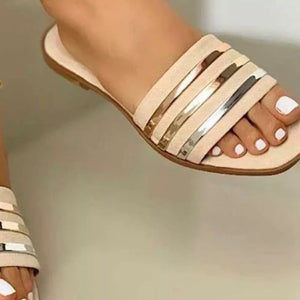 Beige open-toe flat sandals with metallic stripe detail across the vamp.