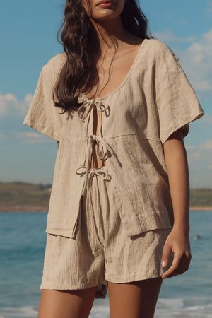 Beige cotton tie-front open top and shorts set with textured fabric.