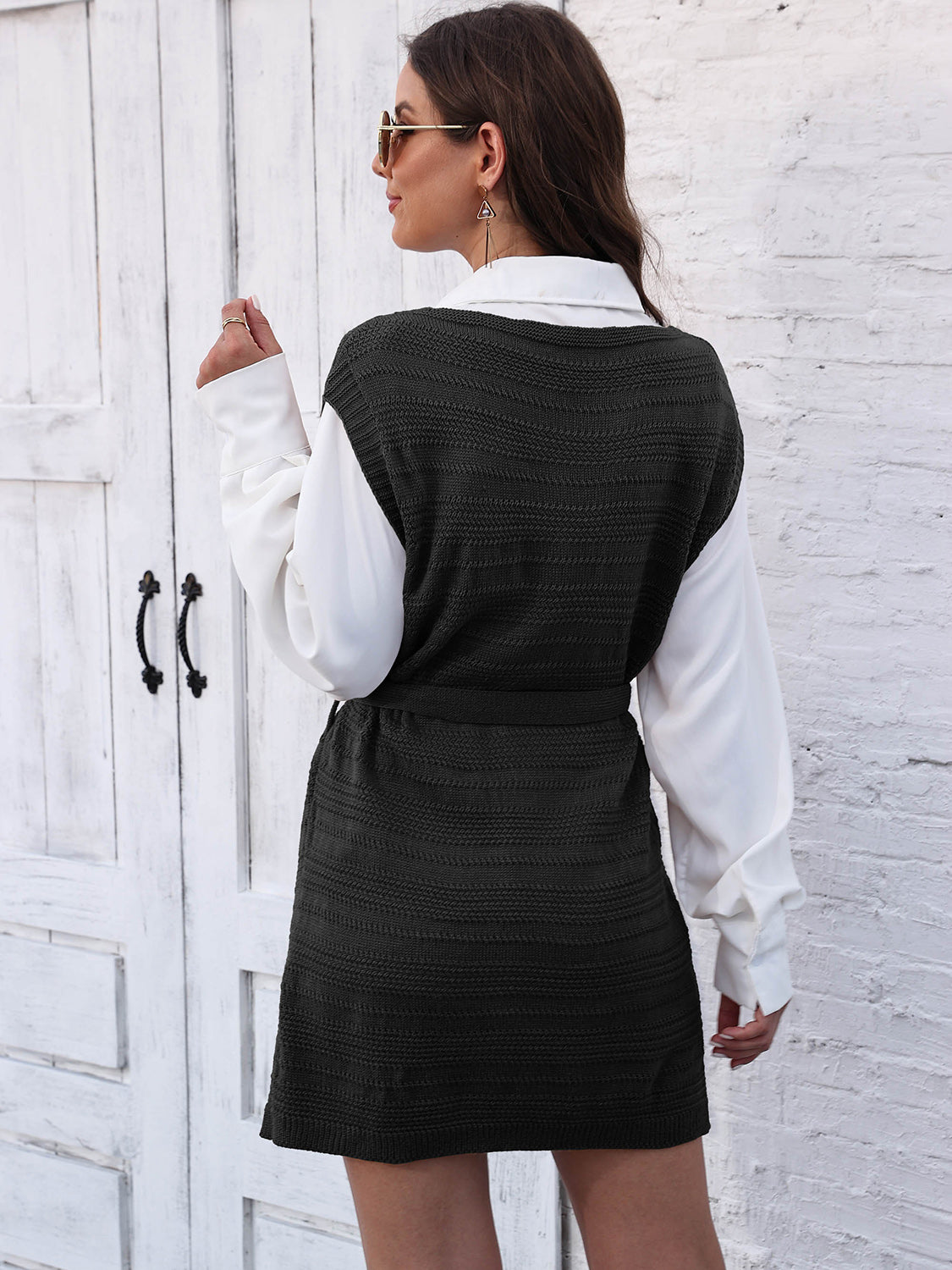 Black knit vest dress with tie and slit, layered over a white shirt.
