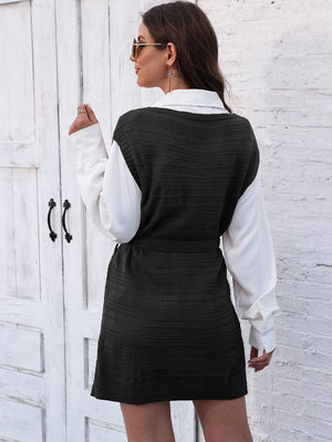 Black knit vest dress with tie and slit, layered over a white shirt.