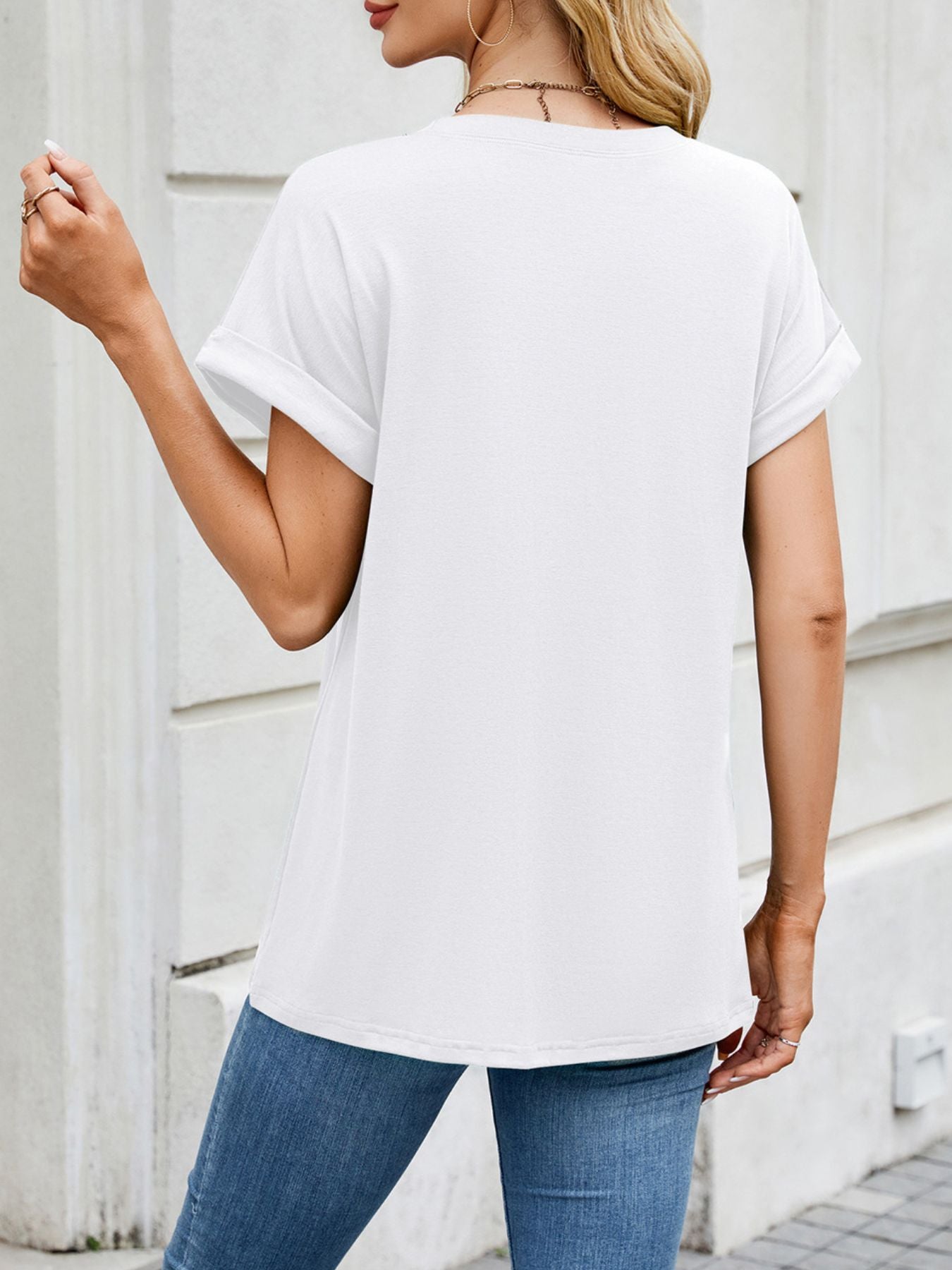 White basic t-shirt with cuffed sleeves and crew neck, styled with jeans.