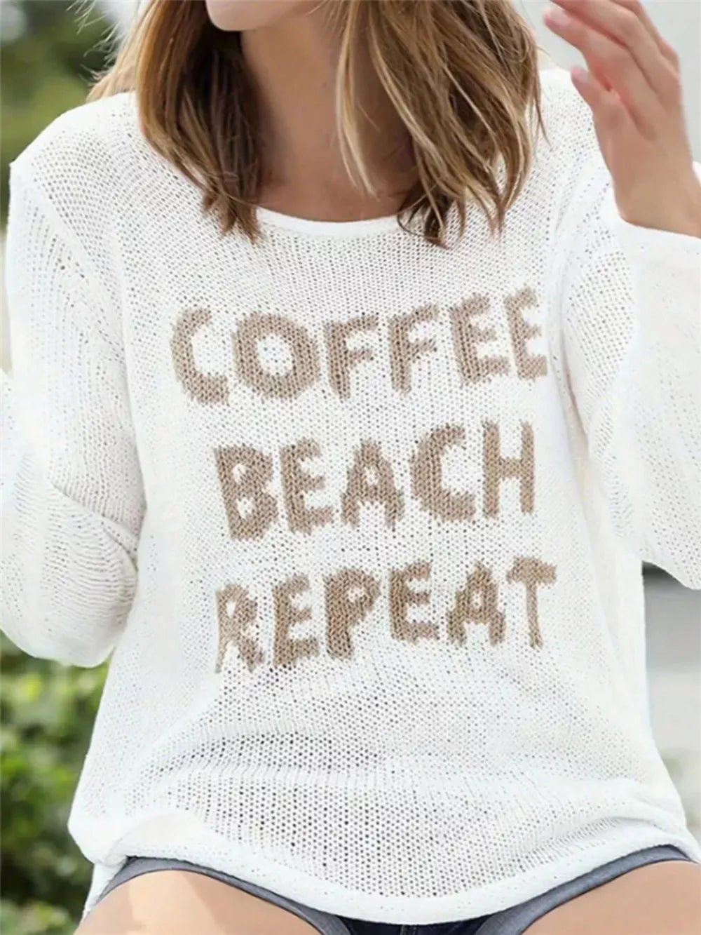 White knit sweater with "Coffee Beach Repeat" graphic, crew neck, and side slits.