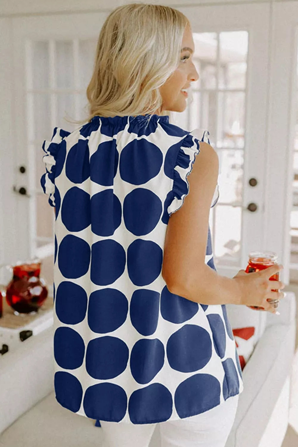 Navy polka dot cami with ruffled neckline and sleeves.