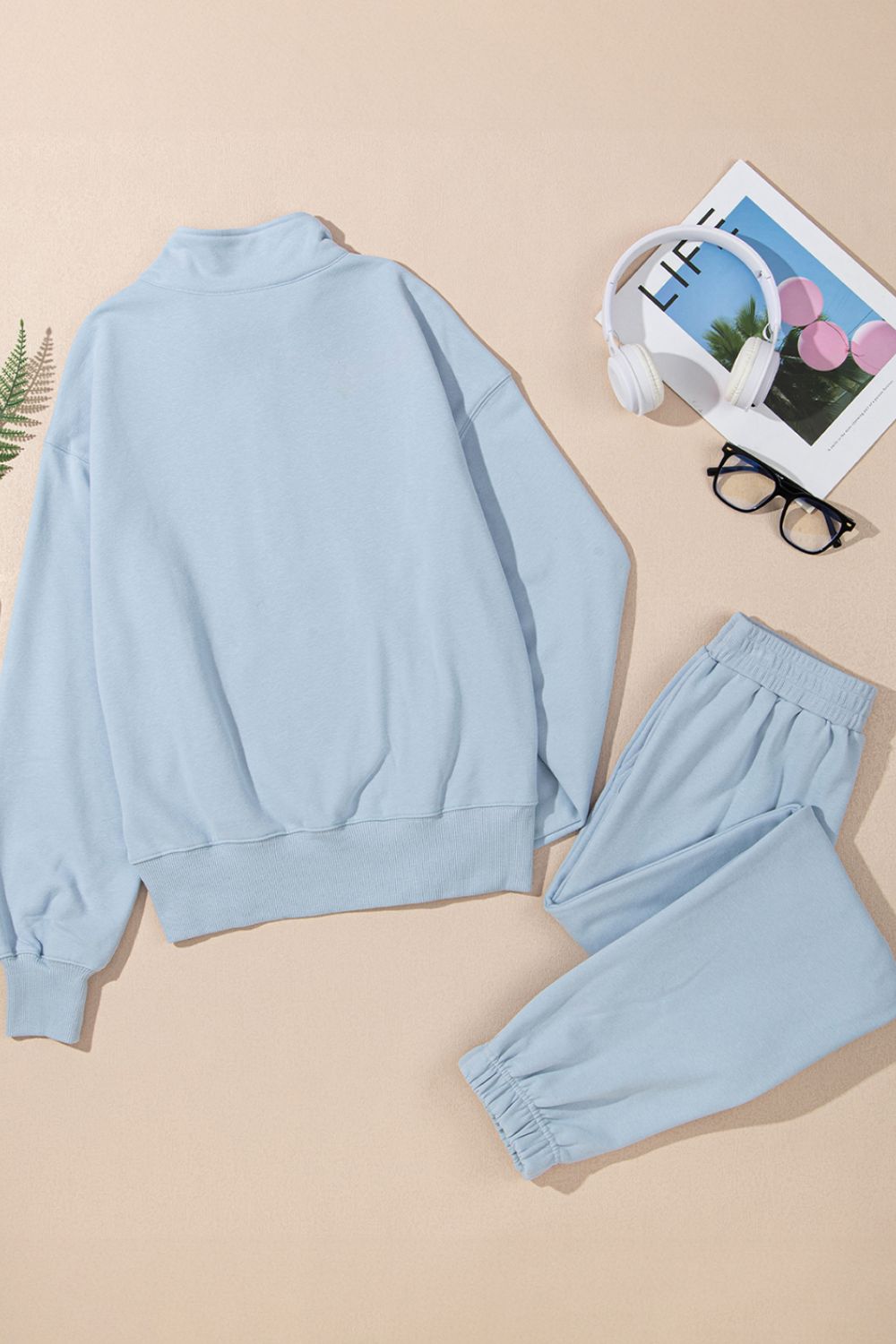 Light blue quarter-zip sweatshirt and jogger set with a mock neck and cuffed ankles.