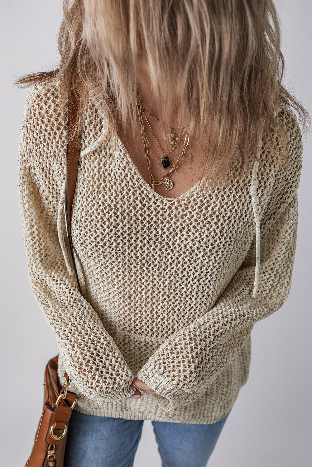 Beige open-knit V-neck hoodie pullover with drawstring details and long sleeves.