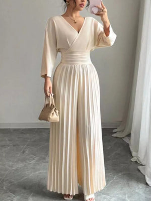 Elegant beige pleated wide-leg jumpsuit with cinched waist and V-neck wrap top.