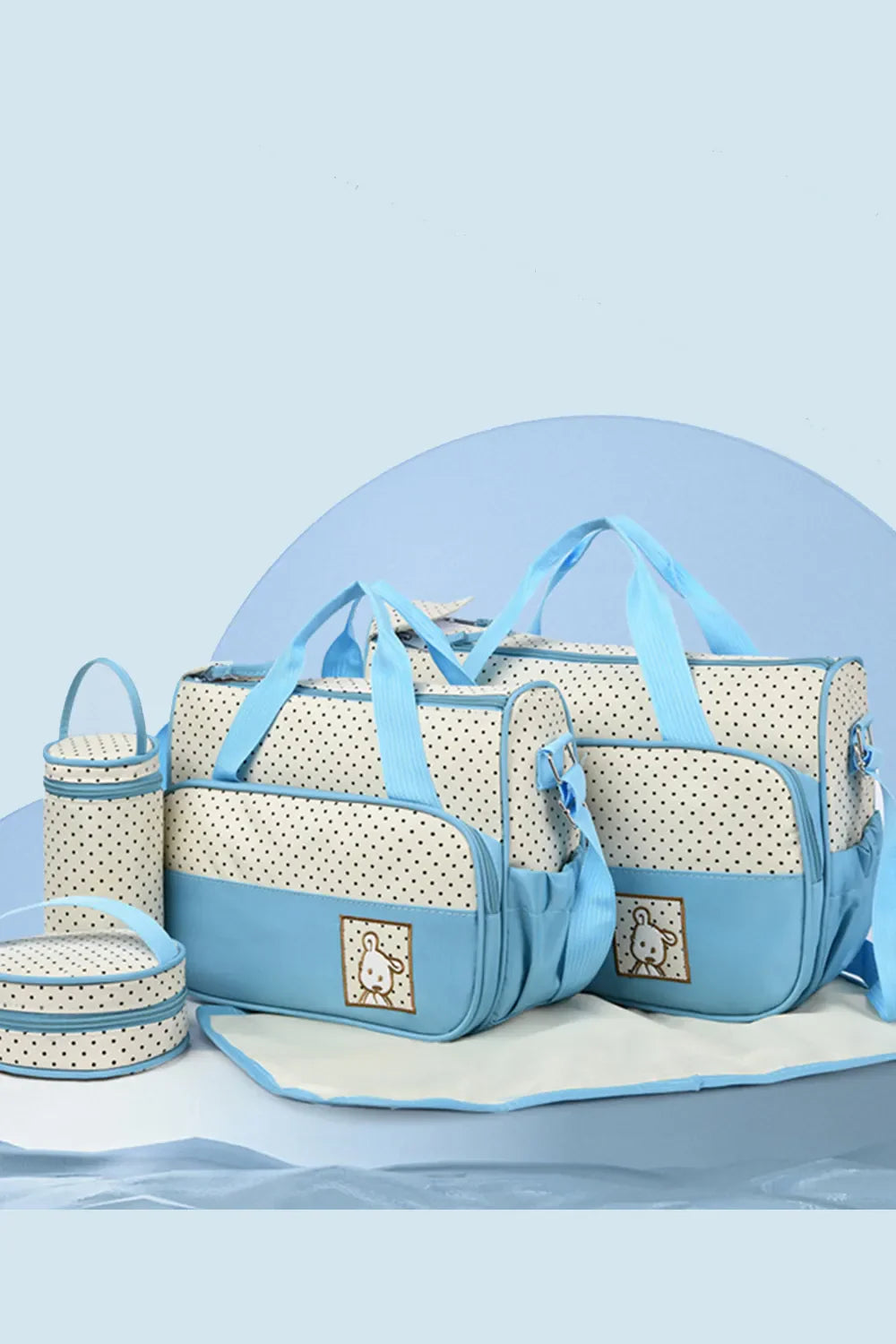 Pastel blue and white polka dot diaper bag set with bunny embroidery and changing mat.