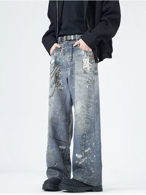 Men's wide-leg jeans in dusty blue denim with paint splatters and chain detail.