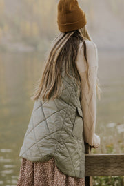 Sage quilted vest coat with diamond pattern and patch pockets, worn over a sweater.