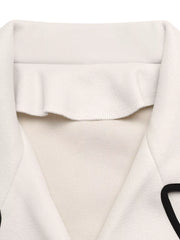 Beige bolero jacket with black contrast trim and ruffled neckline detail.